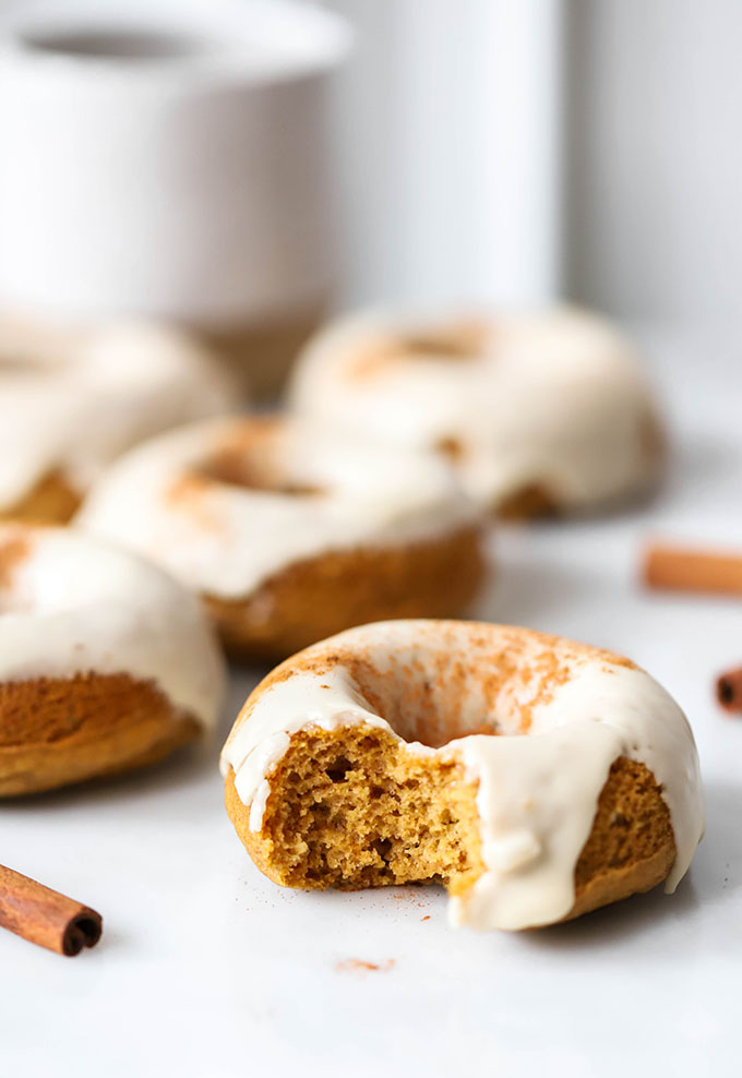 vegan baked pumpkin donuts with maple frosting on white marble