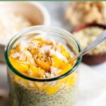 mango chia pudding topped with coconut in a glass with a spoon.