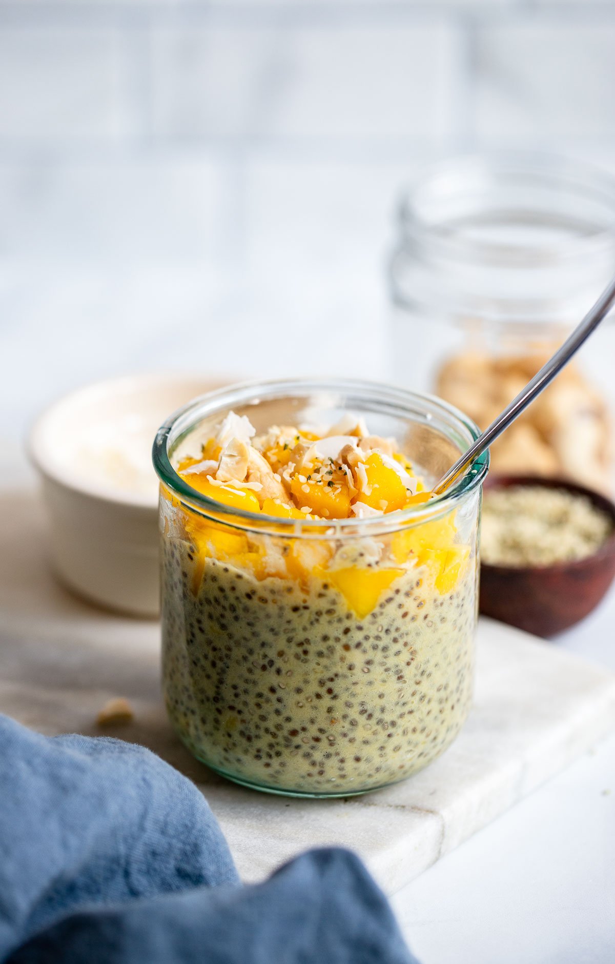 mango chia seed pudding in a glass topped with chopped mango and coconut.