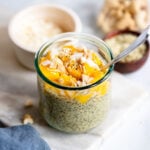 mango chia pudding in a glass topped with coconut flakes.