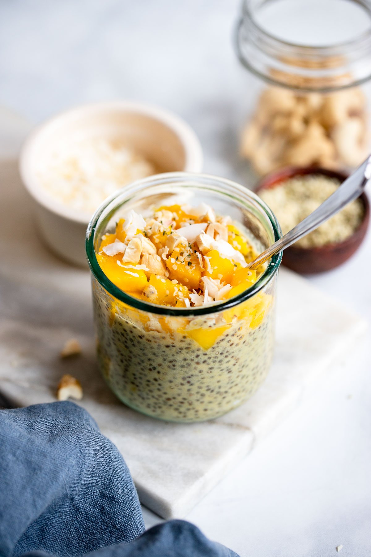 mango chia pudding in a glass topped with coconut flakes. 