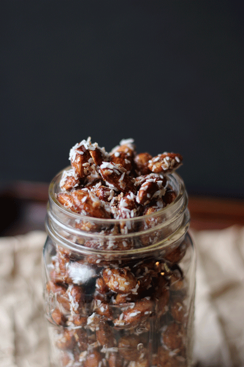 Honey Roasted Cinnamon Almonds in a glass jar on a piece of parchment paper. 