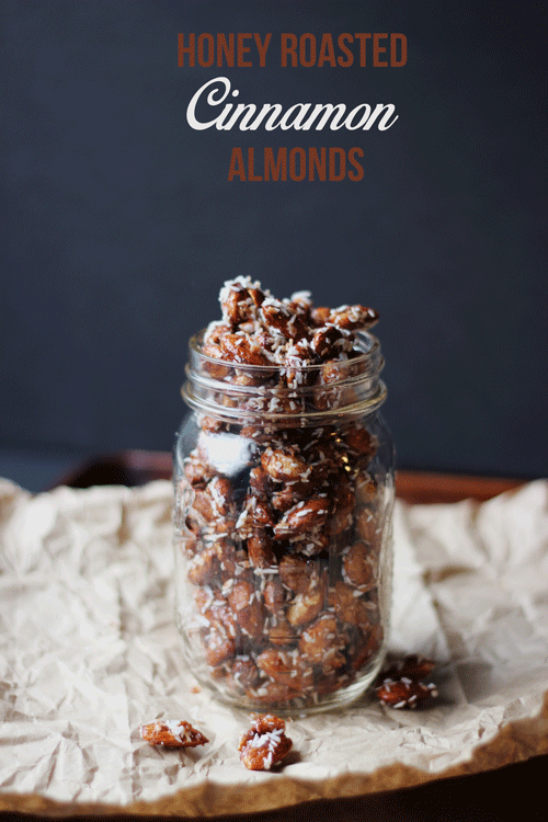 Honey Roasted Cinnamon Almonds in a glass jar on a piece of parchment paper.