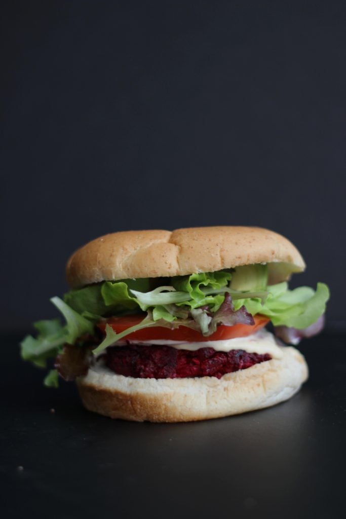 Beet Burger with Garlic Sriracha Aioli close up on a black background. 