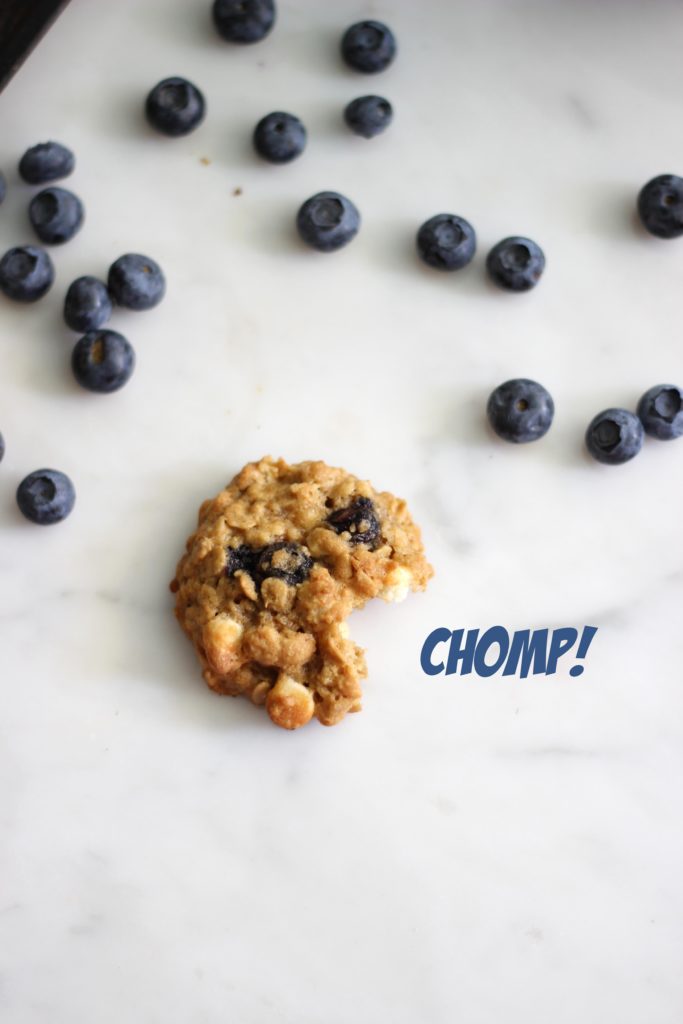 blueberry oatmeal cookie with a bite taken out of it on a white marble background.