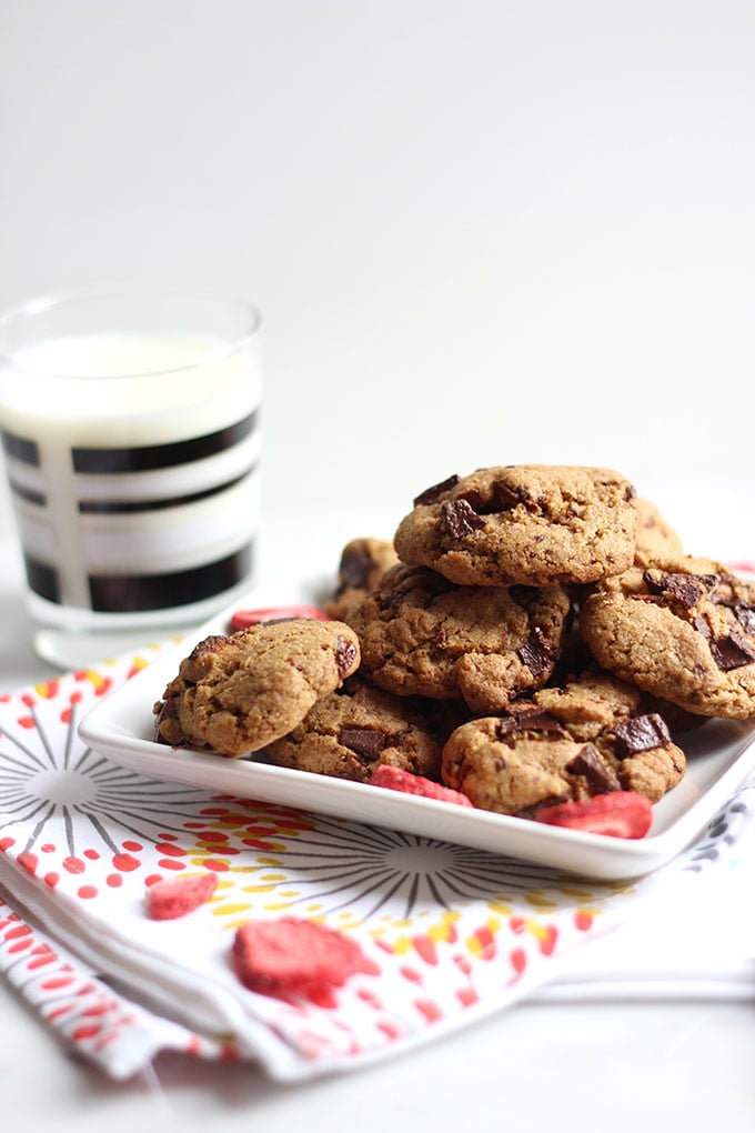 strawberry and chocolate cookies stacked on a square plate on top of a patterned napkin.