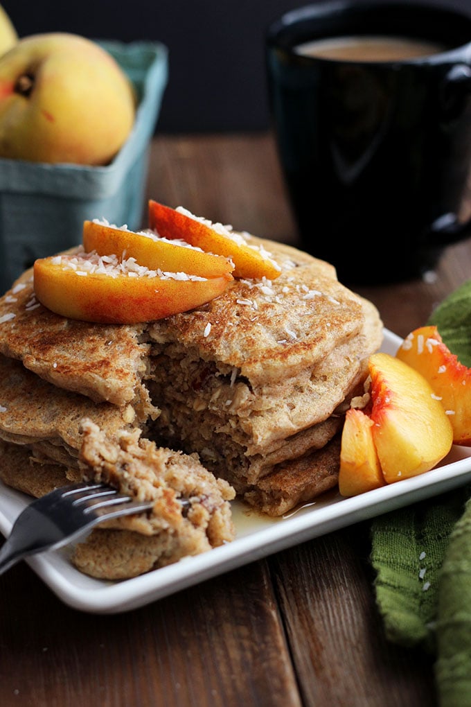 Vegan Oatmeal Pecan Pancakes topped with sliced peaches on a square plate. 