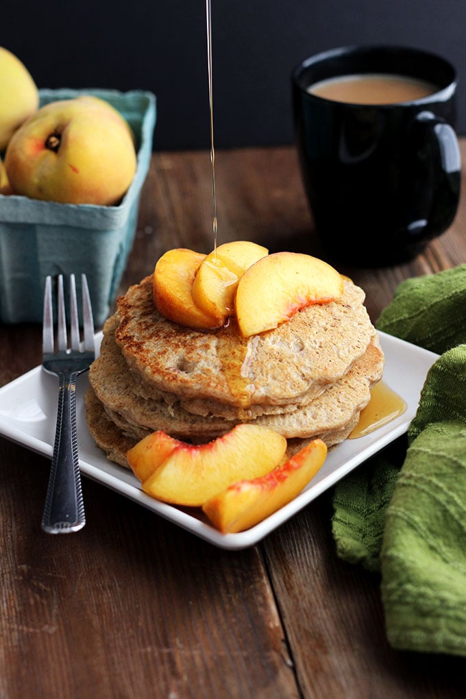 Vegan Oatmeal Pecan Pancakes topped with sliced peaches on a square plate. 