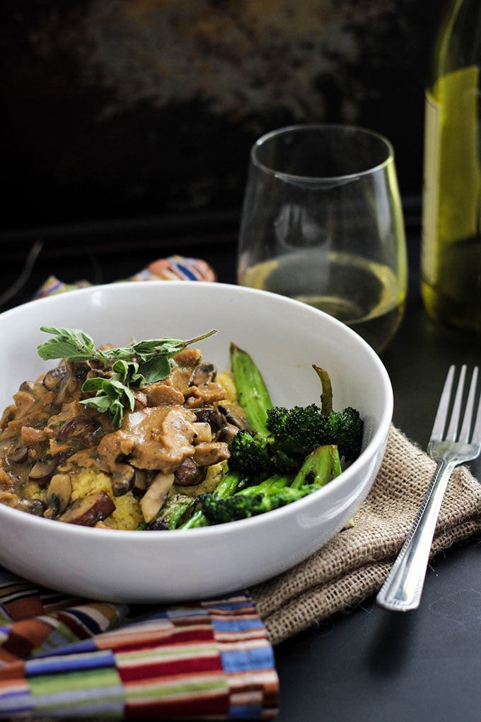 Vegan Seitan and Mushrooms with Polenta in white bowl with fork.