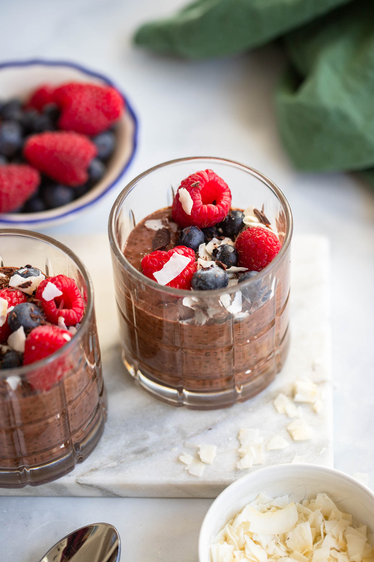 chocolate chia seed pudding in a glass garnished with berries and chocolate shavings. 