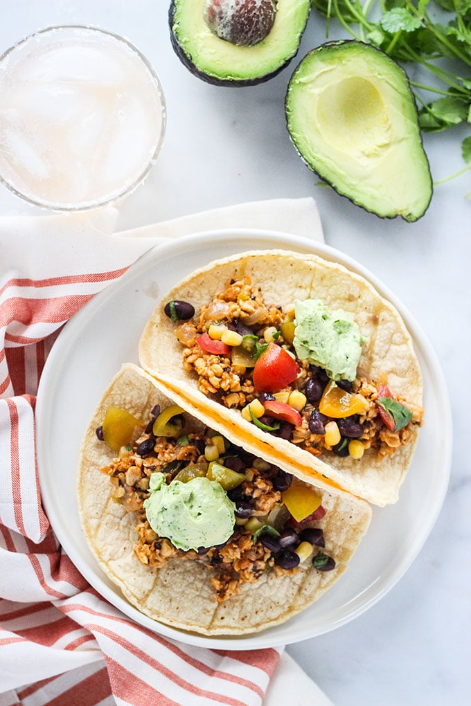 Chipotle Tempeh Tacos with Black Bean Salsa and Avocado Crema on a white plate.