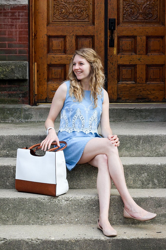 white woman sitting on steps in a blue dress.