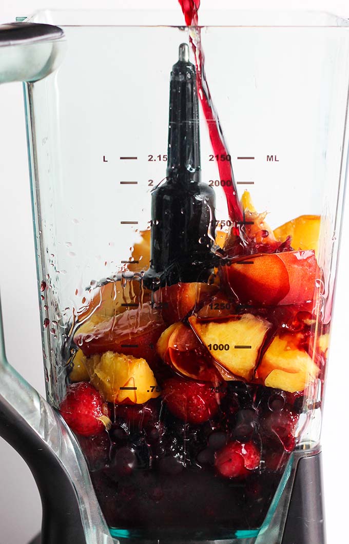 red wine pouring into a blender pitcher with fruit. 