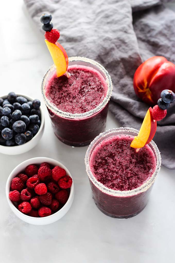 frozen sangria in 2 glasses garnished with fresh berries.