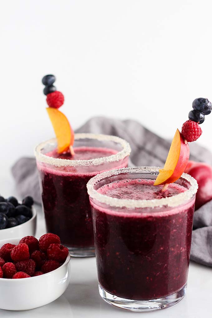 Frozen Berry and Nectarine Sangria in a glass garnished with sugar and a skewer with berries.