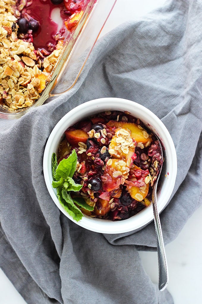 blueberry peach crisp in serving dish with a spoon.