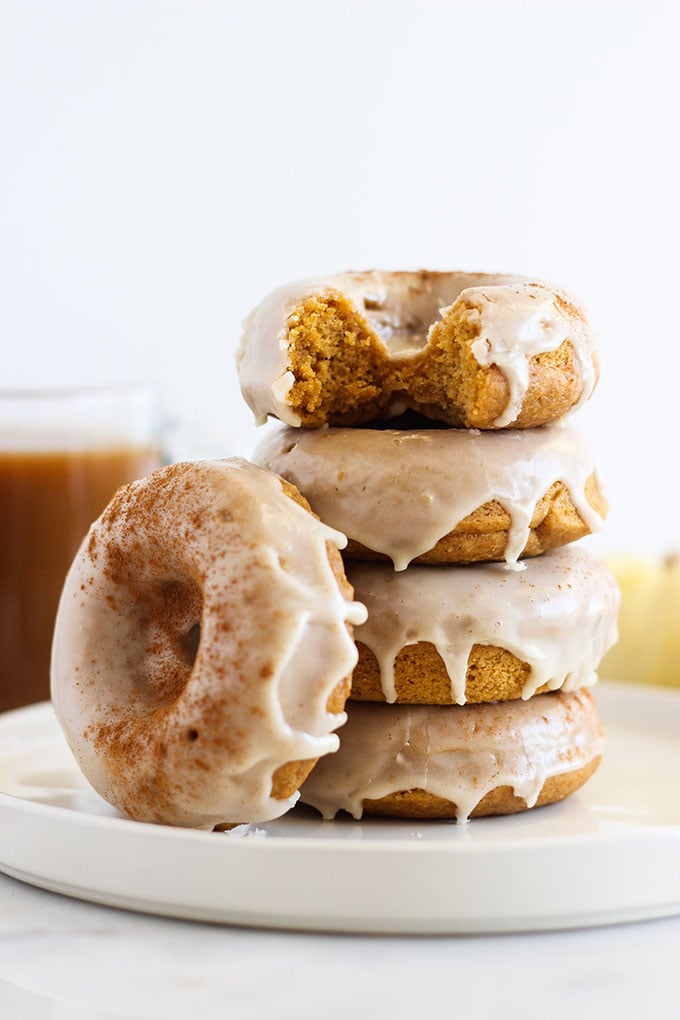 Baked Pumpkin Donuts with Maple Frosting in a stack on a plate.