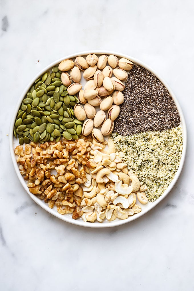 Nuts and seeds arranged on a white plate.