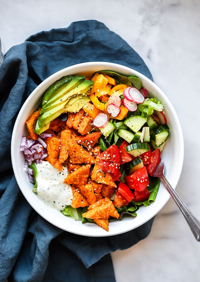 Buffalo Tempeh Salads in bowl with blue napkin.