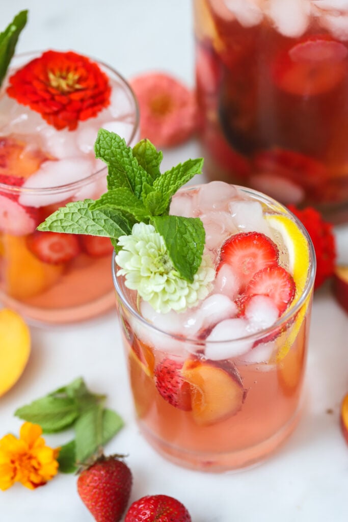 strawberry peach sangria in a glass with strawberries and peaches.