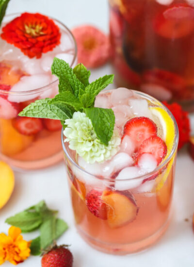 strawberry peach sangria in a glass with strawberries and peaches.