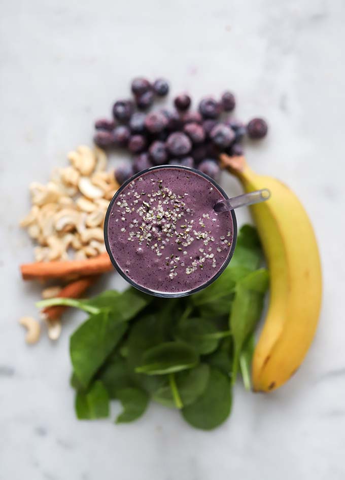 blueberry cashew smoothie with ingredients around the glass. 