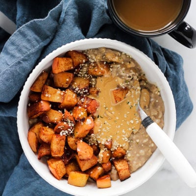 Bowl of oatmeal with sautéed cinnamon apples with blue napkin