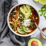 Tortilla soup topped with avocado, lime, and sour cream