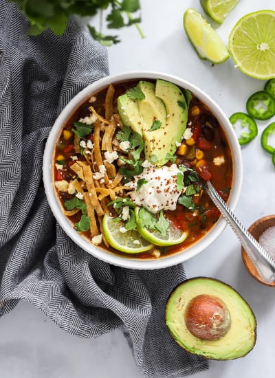 Tortilla soup topped with avocado, lime, and sour cream