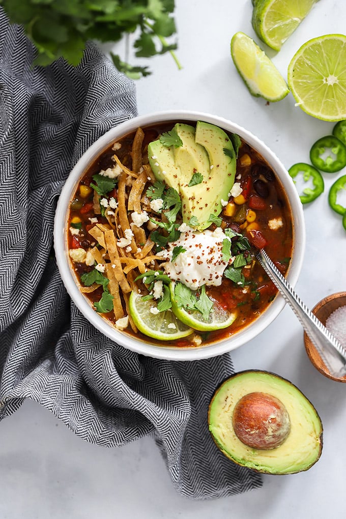 vegan tortilla soup garnished with tortilla strips and avocado.