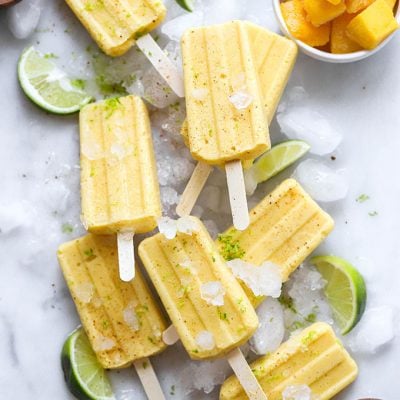 vegan mango lime popsicles on white marble background