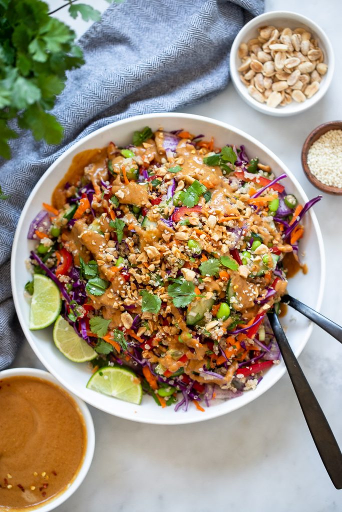 rainbow quinoa salad with peanut dressing in a bowl with a serving spoon. 