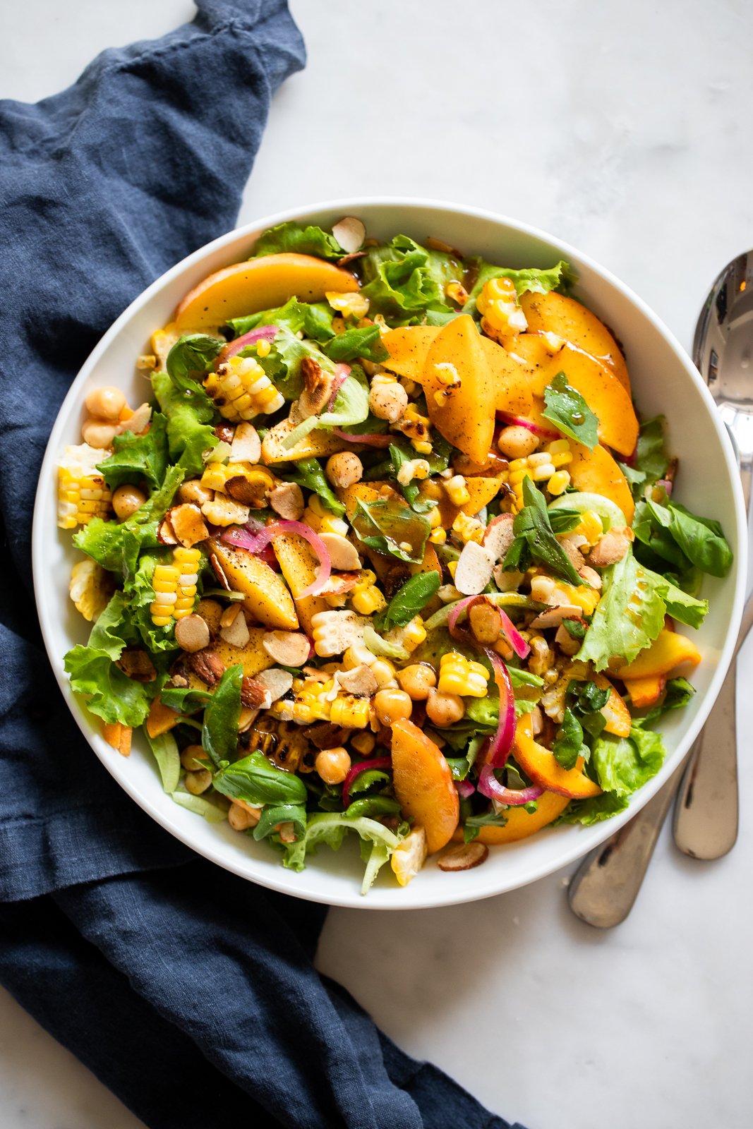 Summer Peach Salad with Grilled Corn and Toasted Almonds in a white bowl