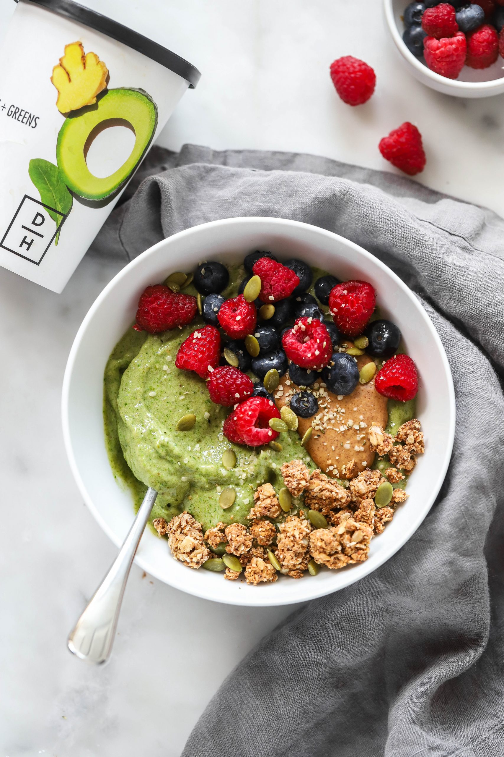 green smoothie bowl topped with berries, nut butter, and granola.