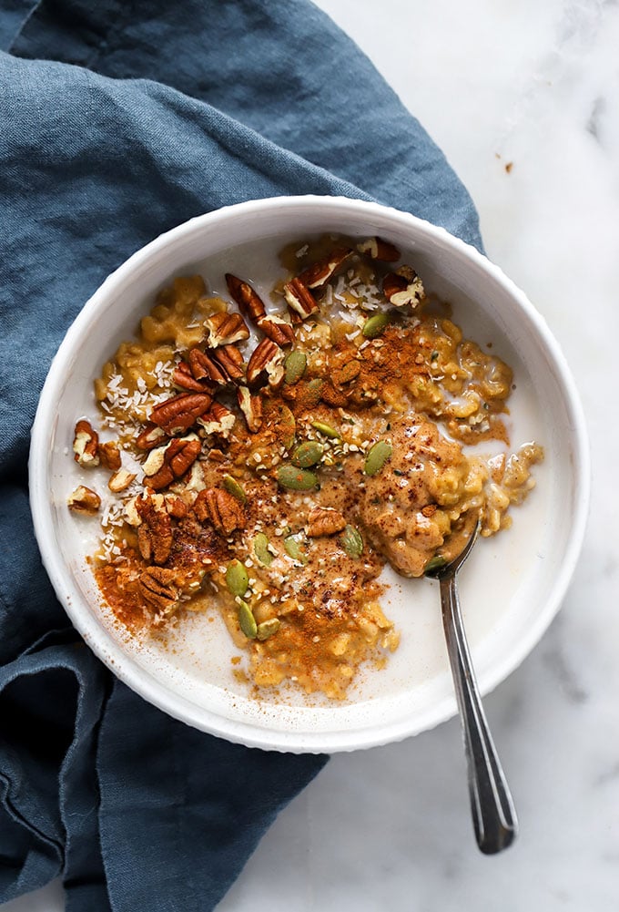 pumpkin oatmeal in bowl with nut butter, pumpkin seeds, and pecans.