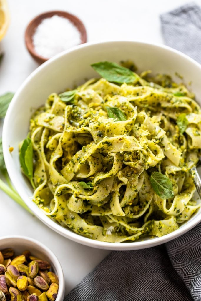 vegan pesto pasta garnished with fresh basil and lemon zest