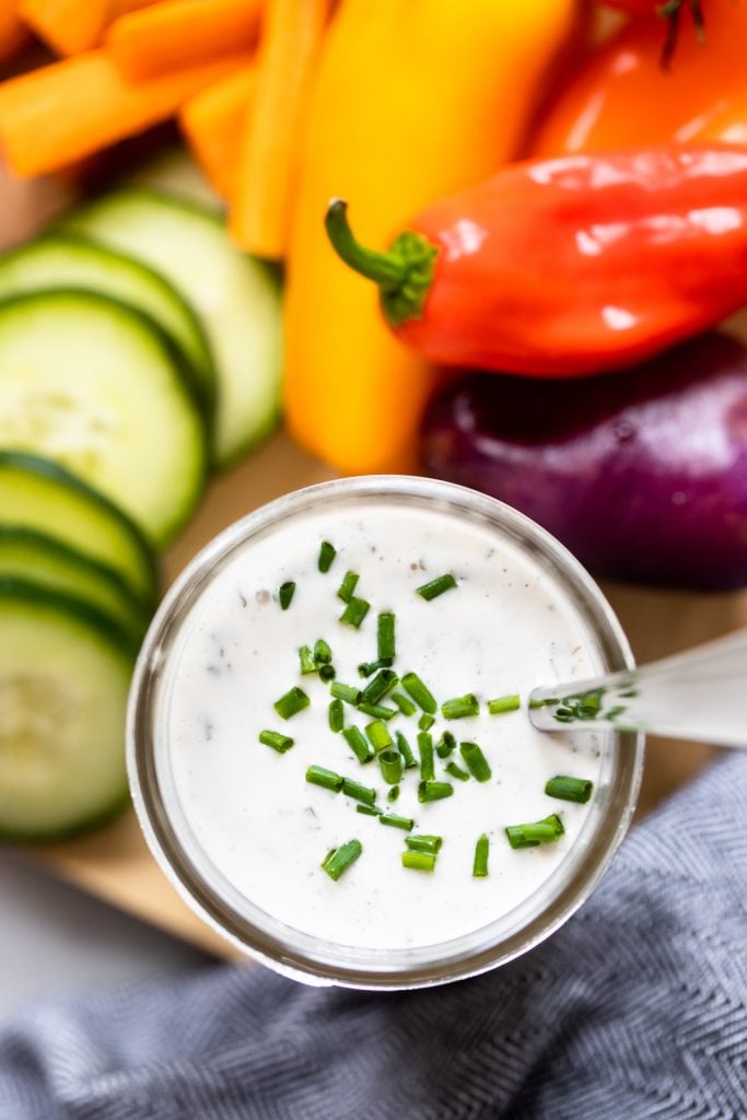 homemade vegan ranch dressing in jar with colorful vegetables. 