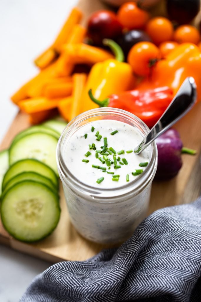homemade vegan ranch dressing in a jar garnished with chopped chives. 