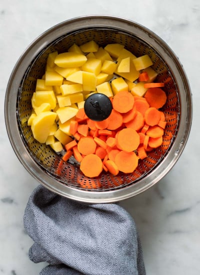 carrot and potato in steamer basket before cooking.