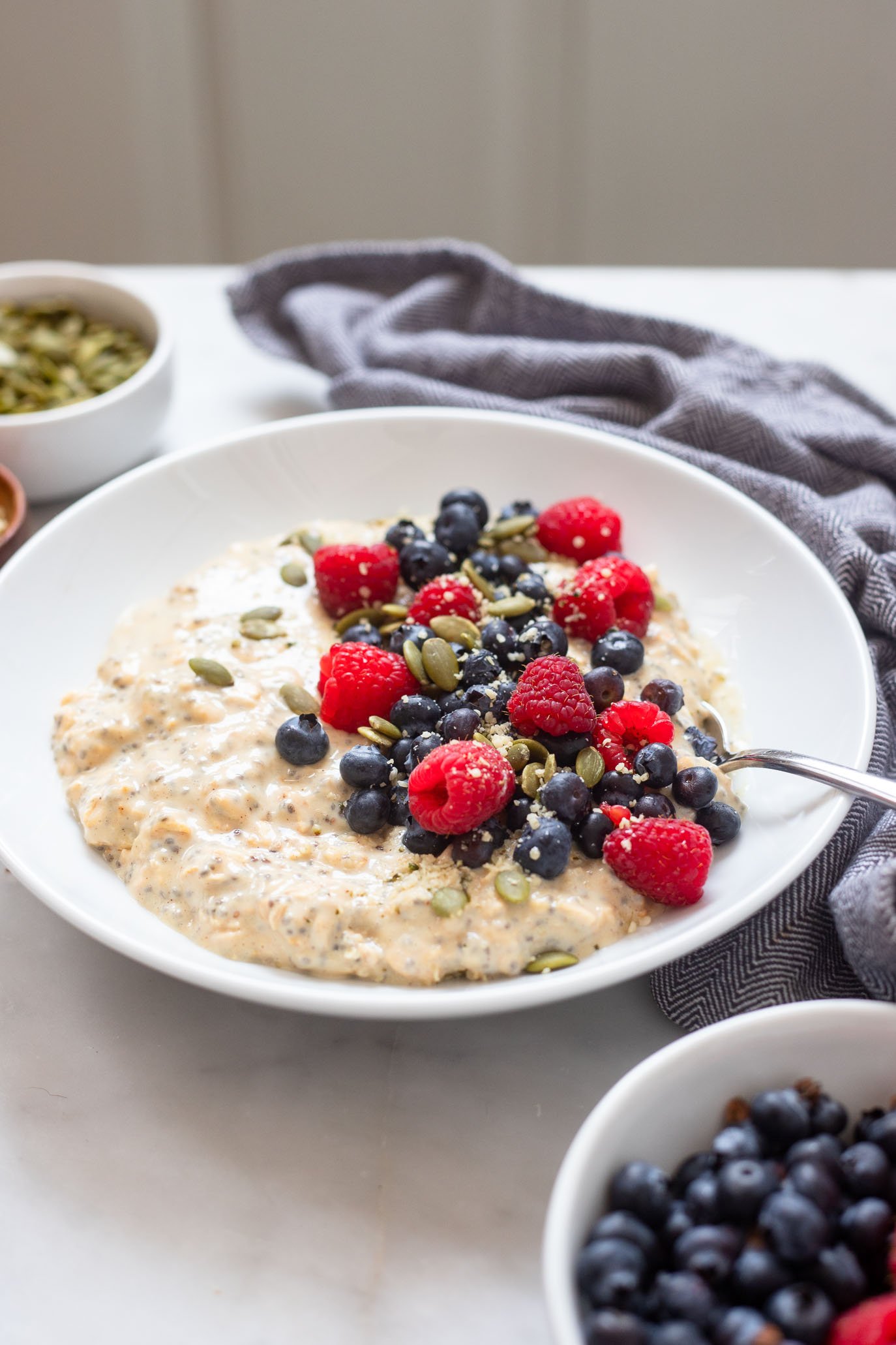 vegan protein overnight oats in bowl garnished with fresh berries and pumpkin seeds. 