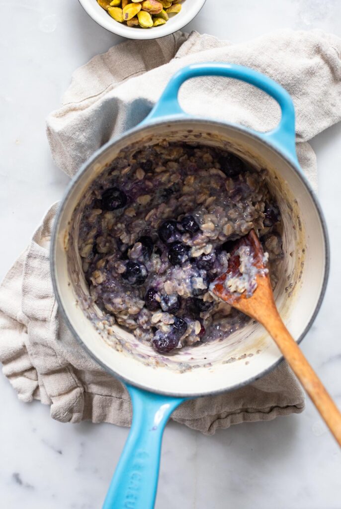 cooked oatmeal in saucepan with blueberries stirred in