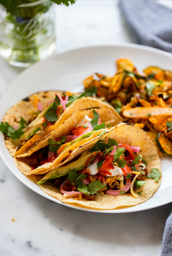 easy vegan tacos with seitan on a plate garnished with cilantro and picked red onion. 