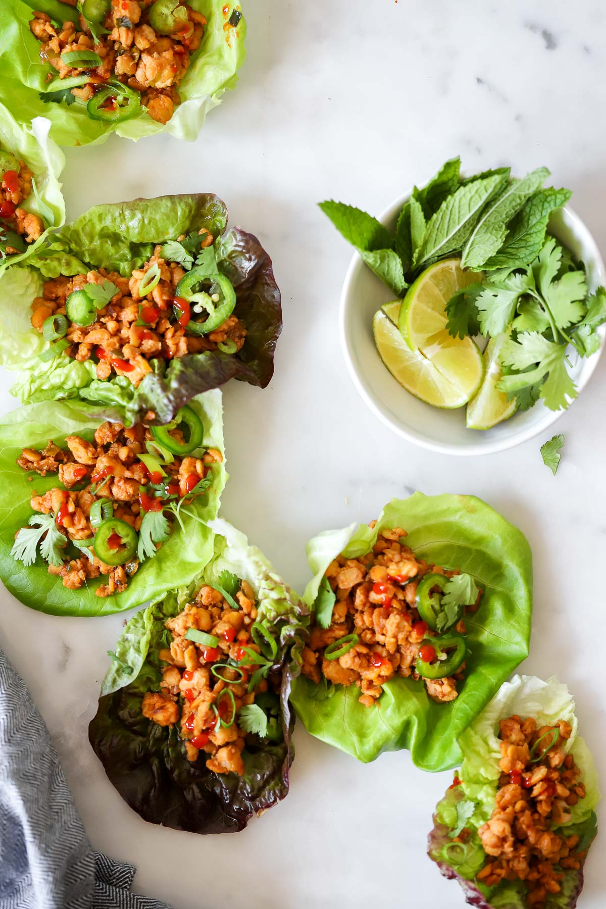 tempeh lettuce cups on table garnished with cilantro and jalapeño.