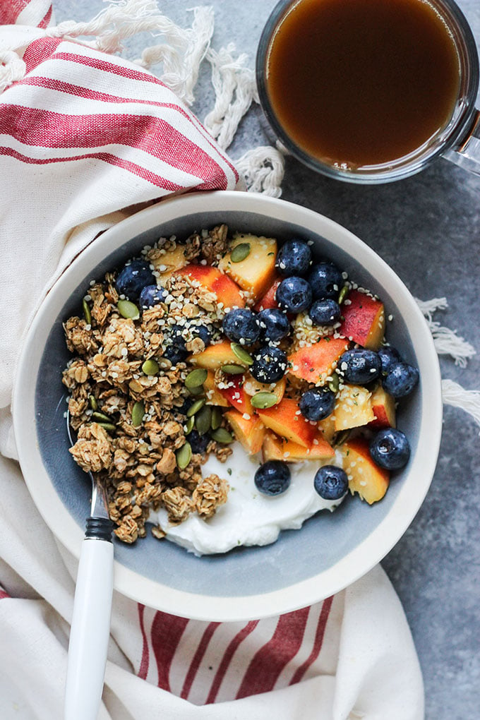 bowl of yogurt with homemade granola, peaches, and blueberries. 