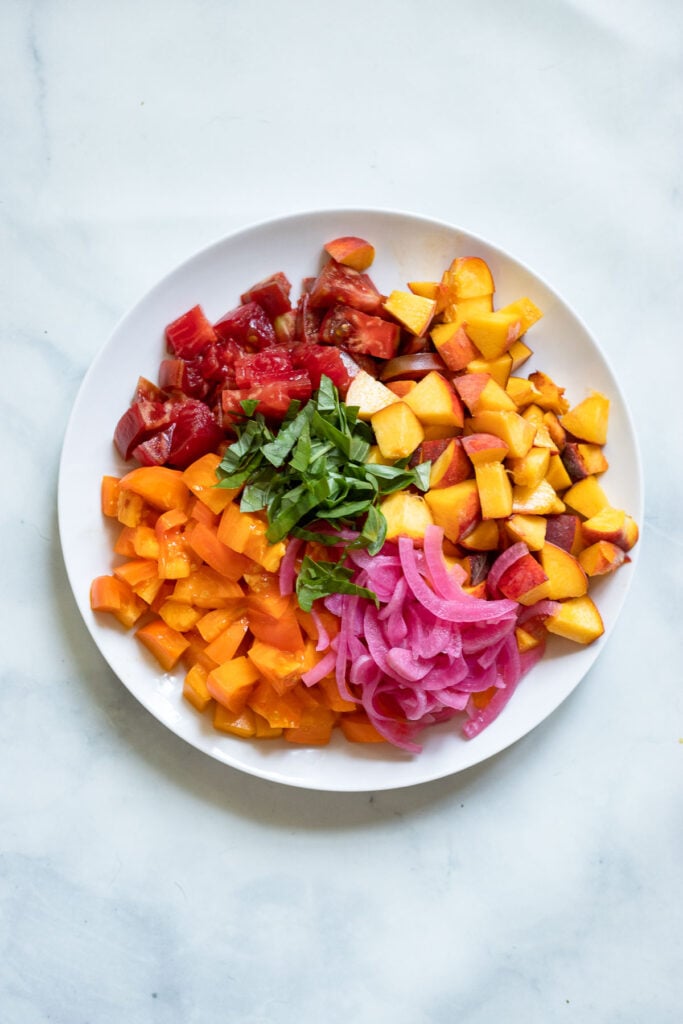 chopped tomatoes, peaches, pickled red onion, and basil on plate