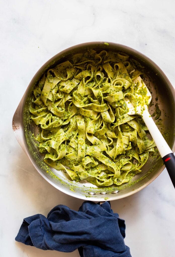 pesto and pasta stirred together in a skillet