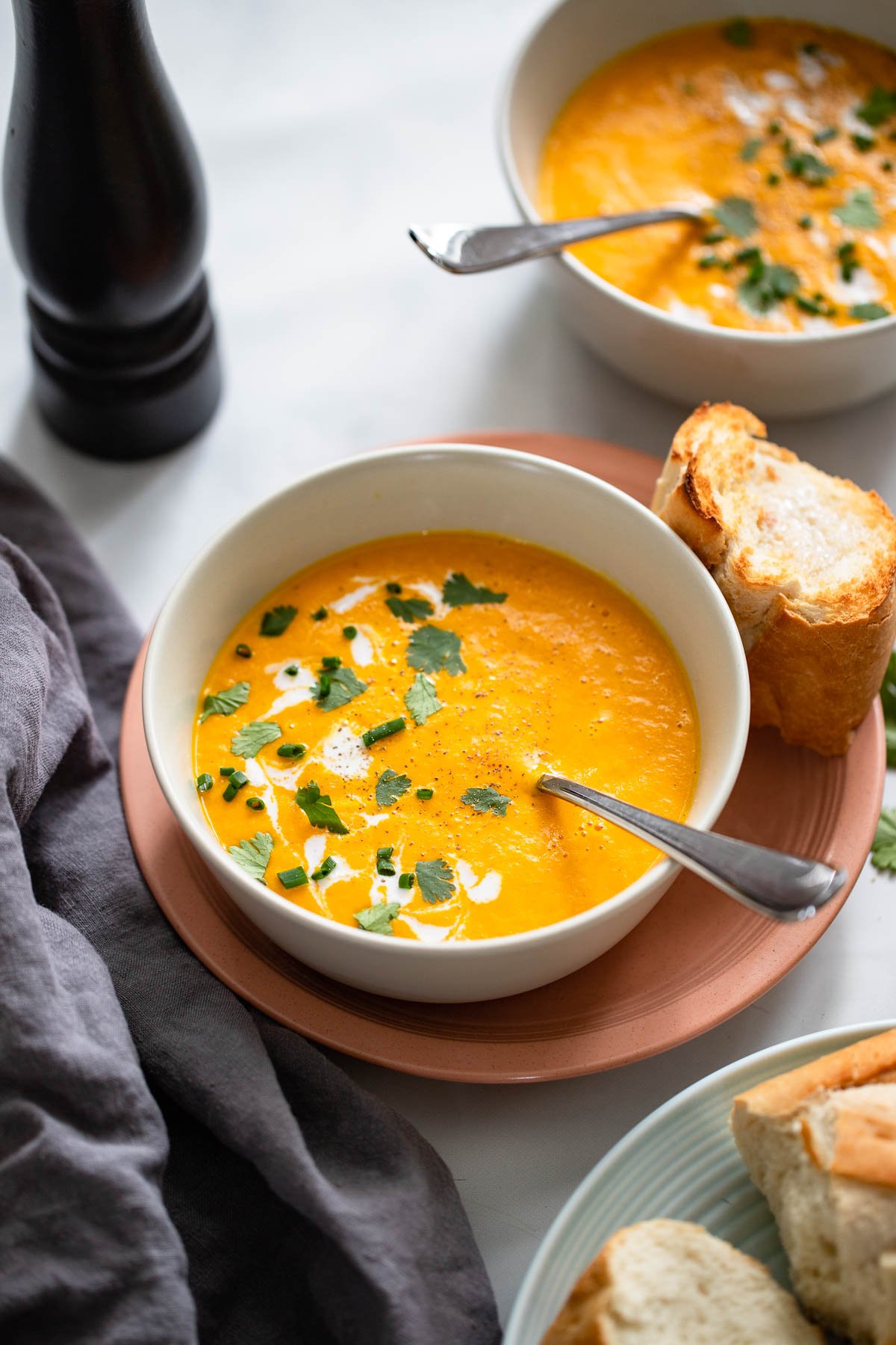creamy carrot soup garnished with cilantro, chives, and coconut milk.