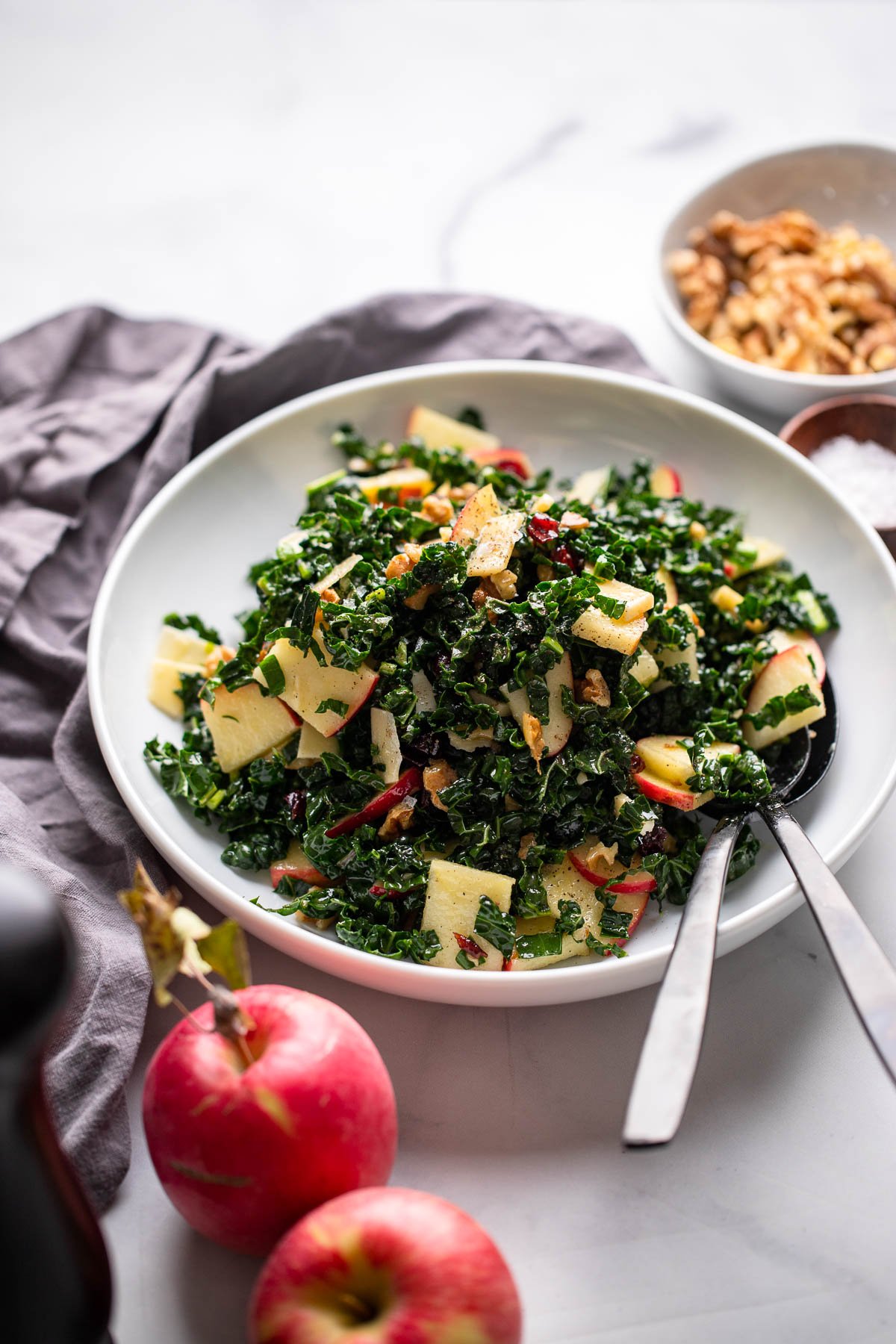 kale apple walnut salad in white bowl.