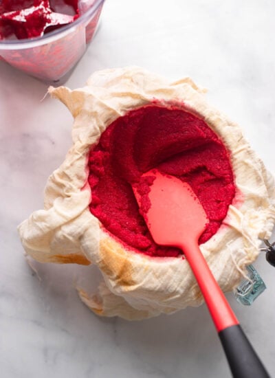 pureed beet juice pulp in a strainer lined with cheesecloth.