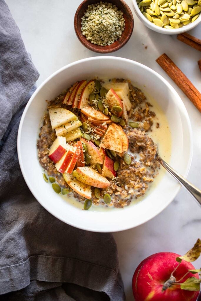 cinnamon oatmeal topped with apples and pumpkin seeds.